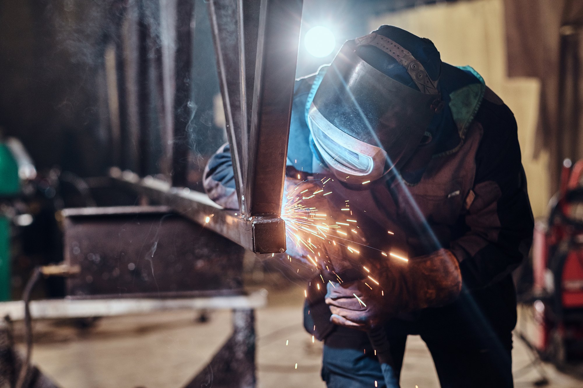 Welder fabricating a steel frame in a metalworking workshop