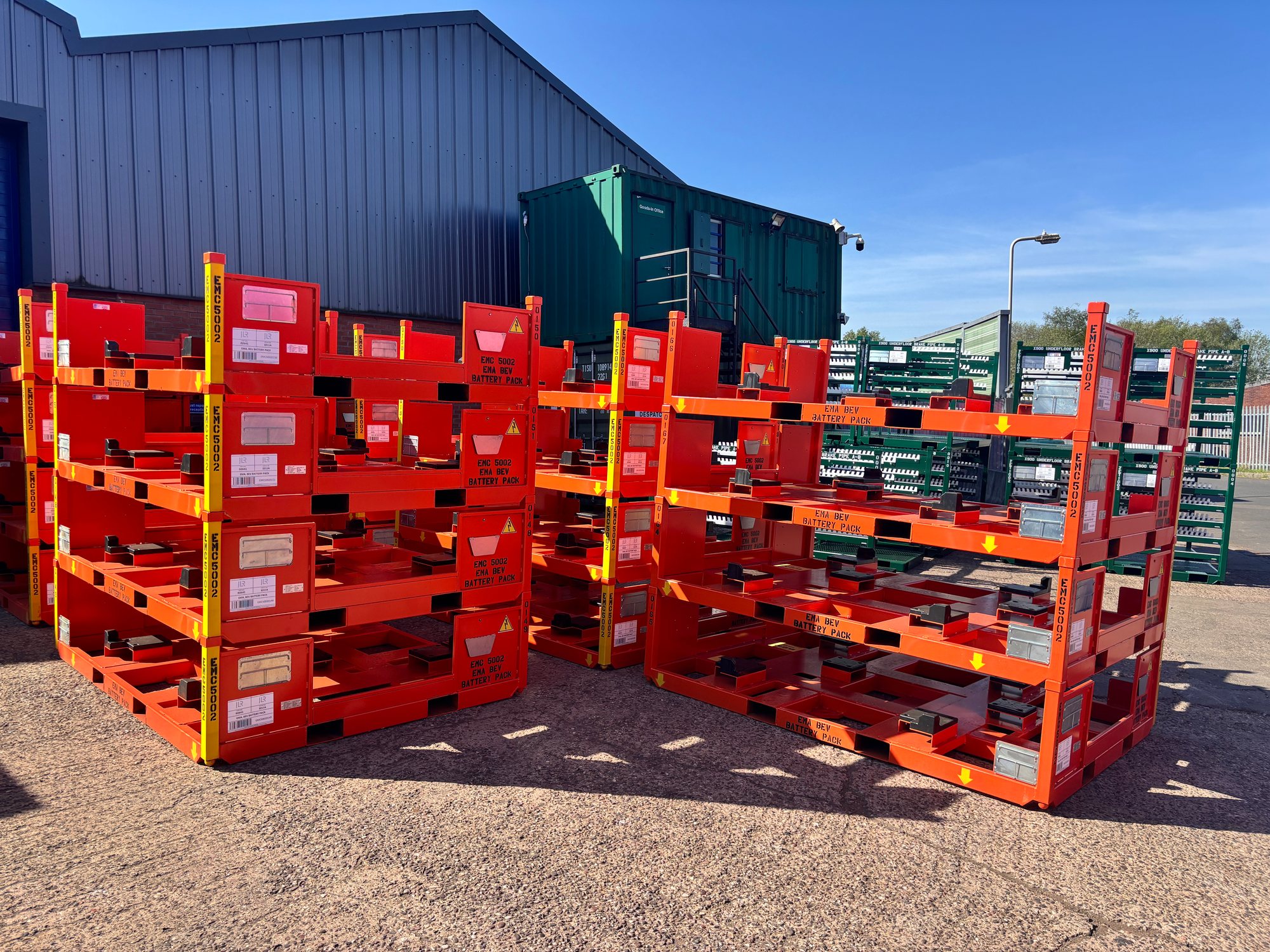 Red automotive battery-pack stillages outside the Bache Pallets workshop